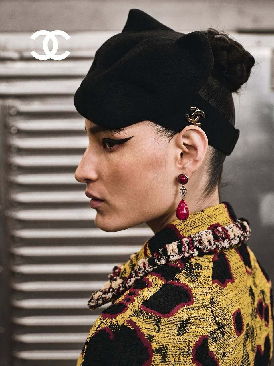 Chanel — профиль модели в чёрном берете с красной серьгой и логотипом CC